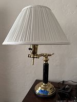 Vintage brass and marble table lamp with pleated white fabric shade, showing entire lamp on wooden surface