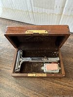 Chrome vintage safety razor inside a wooden box with a small shaving soap block