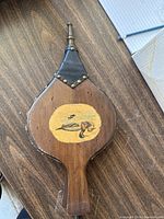 Top view showing wooden body with a hand-painted small decorative design in yellow oval and some minor scratches