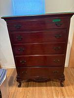 Full front view of the tall vintage wooden dresser showing five drawers and the glass top.