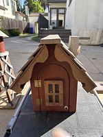 Front view of the wooden barn mailbox showing the roof design, hinged door with window, and brass hinges.