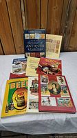 Photo showing a stack of 8 collectible books including an antiques dictionary, beer book, toy collectors guides, and other collectible titles.