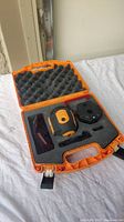 Open orange plastic case showing Johnson laser level and accessories neatly placed in foam padding.