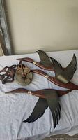 Rustic primitive decor pieces including metal bird sculptures with wings on wooden supports and vintage rusty pulley wheels.
