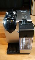 Front view of DeLonghi Nespresso Lattissima EN520SL showing brew head, drip tray and milk container