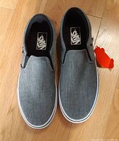 Top view of both grey slip-on Vans showing uppers and size tags