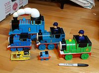 Group view of six Thomas & Friends plastic toys on floor
