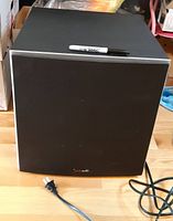 Front view of Polk Audio subwoofer showing grille and power cord