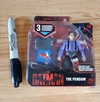 Front of sealed Penguin figure package beside marker for scale