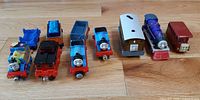 Eight Thomas & Friends vehicles and cars lined up on floor