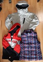 Group shot of three outerwear items: grey hooded Columbia jacket, red/black Canada Olympic Bay jacket, plaid Tommy Hilfiger vest