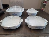 Four Corning Ware Blue Cornflower casserole dishes with lids, displaying floral pattern and overall condition