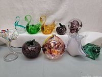 All nine glass figurines arranged in two rows on white surface and background