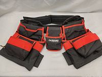 Full front view of the Husky tool belt showing multiple pockets, zippered compartments, and padded adjustable strap.