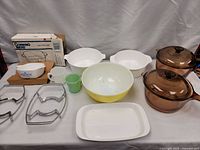 Full lot of kitchenware furniture arranged on table, showing packaging box and multiple bowls, cups, and glass bakeware pieces