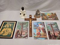 Overall photo showing all items in the lot including framed print, crucifix, laminated prints, and figurines.