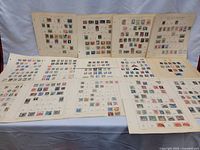Multiple cream album pages laid out showing vintage stamps from diverse countries including Netherlands and Austria.