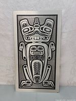 Front view of the metal plaque showing the black and white stylized beaver design within a silver-tone frame.