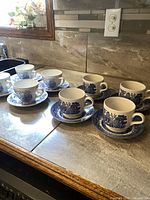 First photo shows both sets of cups and saucers arranged on countertop, displaying Blue Willow and Countryside patterns.