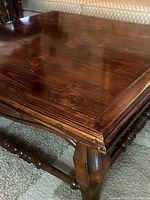 Close-up of the polished wood surface and carved edge of the square coffee table showing wood grain and finish condition.