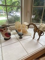 Full lot showing ceramic bird pitcher, onyx knight bookends, brass giraffe, and small bird figurine on a windowsill