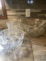 Overall view of the large cut glass crystal bowl, smaller bowl, four small vases, plastic ladles inside large bowl, and small crystal bowls stacked