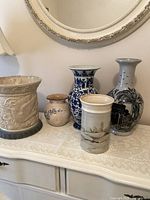 Full set of five vintage vases displayed on table with mirror background showing variety in style and size