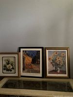 Set of three framed prints placed side by side on a surface against a plain wall, showing overall condition and presentation.