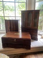 Set of three vintage wooden jewelry boxes shown together near a window, two upright and one flat box in front