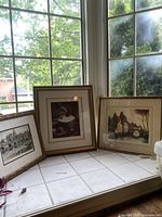 Five framed landscape prints arranged on a windowsill showing the variety of artwork and frames.