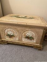 Side view of small wooden trunk with hand-painted white magnolia flowers and antique cream finish