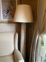 Full view of the vintage ceramic column floor lamp showing lamp base, shade, and surrounding area including chair and wall art.