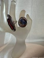 Two rings displayed on frosted hand stand showing both designs