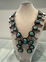 Full front view of squash blossom necklace on fabric-covered bust display
