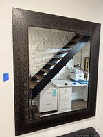 Full view of the rectangular wall mirror showing textured metallic frame and clear reflective glass.
