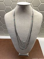 Necklace displayed on bust, showing five silver strands with turquoise beads spaced across them.