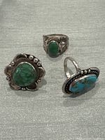 Three silver rings with turquoise stones arranged on gray fabric, showing overall lot