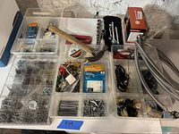 Wide view showing the hammer, socket set, solar deck lights, plastic organizers with screws and nails, hose pipes, and various small hardware items arranged on a white surface.