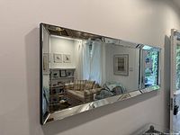 Full view of the large rectangular mirror on the wall showing the glass frame and interior room reflection