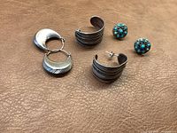 Overview of all three pairs of earrings on brown textured surface showing shape, size, and colors.