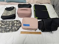 Full lot of 7 small storage bags including patterned, black and pink designs on bed with ruler for scale