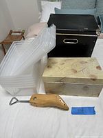 Full set showing all storage boxes and shoe stretcher on bed, clear plastic boxes stacked, black box behind them, decorated cardboard box in front, wooden shoe stretcher in front.