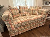 Front view of the plaid multicolor fabric loveseat with three cushions visible, showing fabric pattern and overall shape.