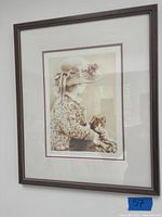 Framed sepia print showing girl and cat, with a sticker number 57 on frame corner.