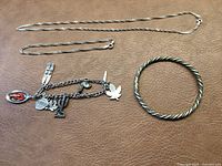 All four items of stamped sterling silver jewelry laid out on a brown surface.