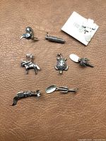 Top view of all 8 sterling silver charms arranged on a brown leather surface showing various animal and object shapes.