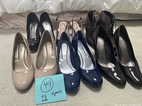 Six pairs of assorted women's high-heeled shoes size 9.5 arranged in two rows showing front views and colors: black, beige, navy blue, brown.