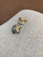 Front view of both earrings on light fabric showing shell motif and high polish finish