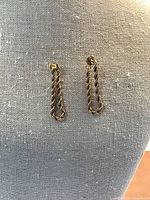 Pair of twisted rope earrings displayed on fabric background