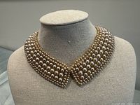 Full view of the wide pearl cuff bracelet displayed on a neutral fabric bust, showing the overall design and shape.